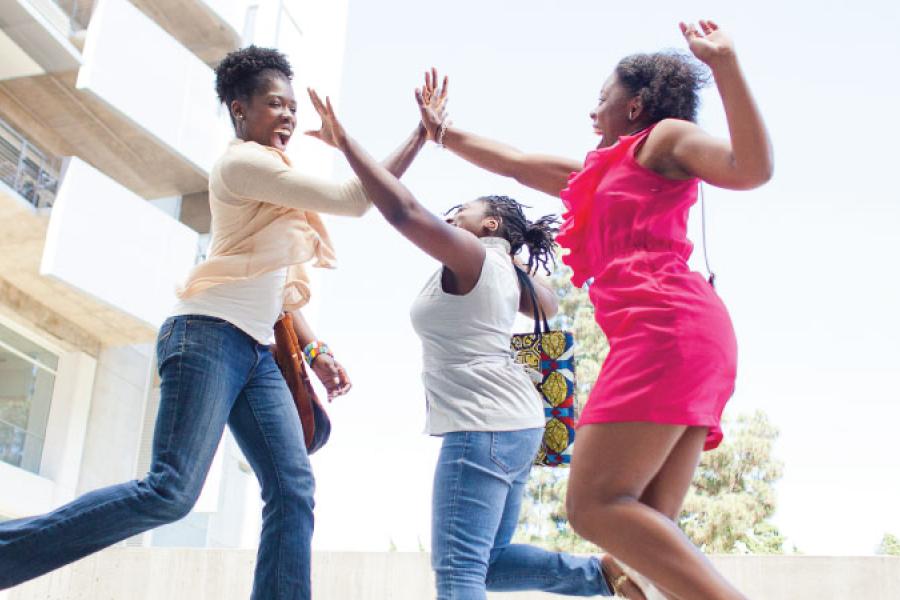Three Black women jumping to high five eachother