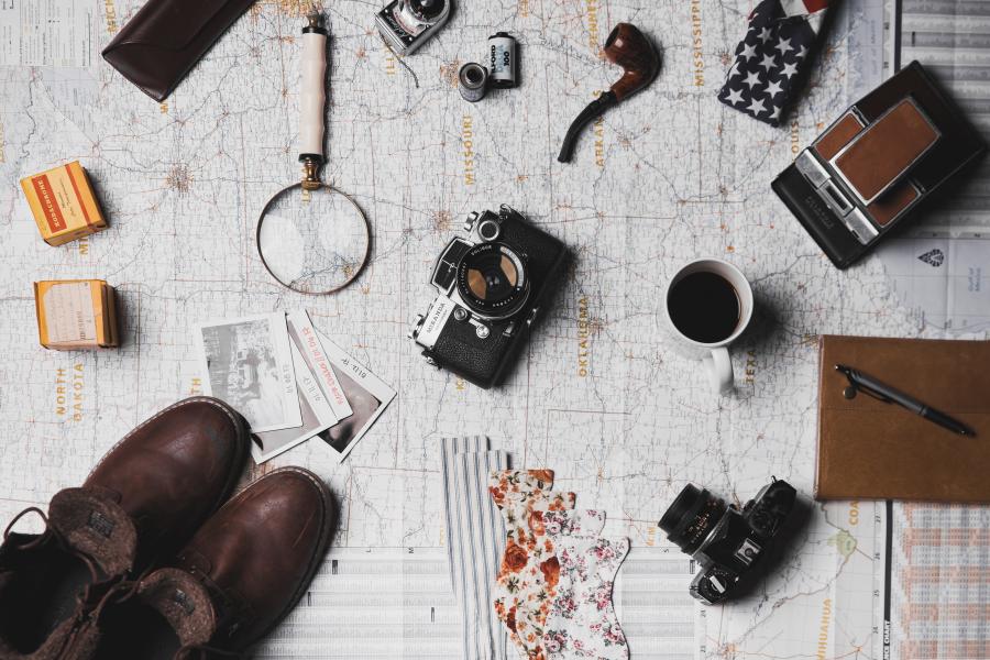 Travel items: shoes, cameras and more laid out across a map