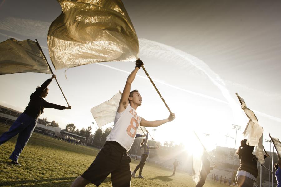 Students dancing together with flags on a field
